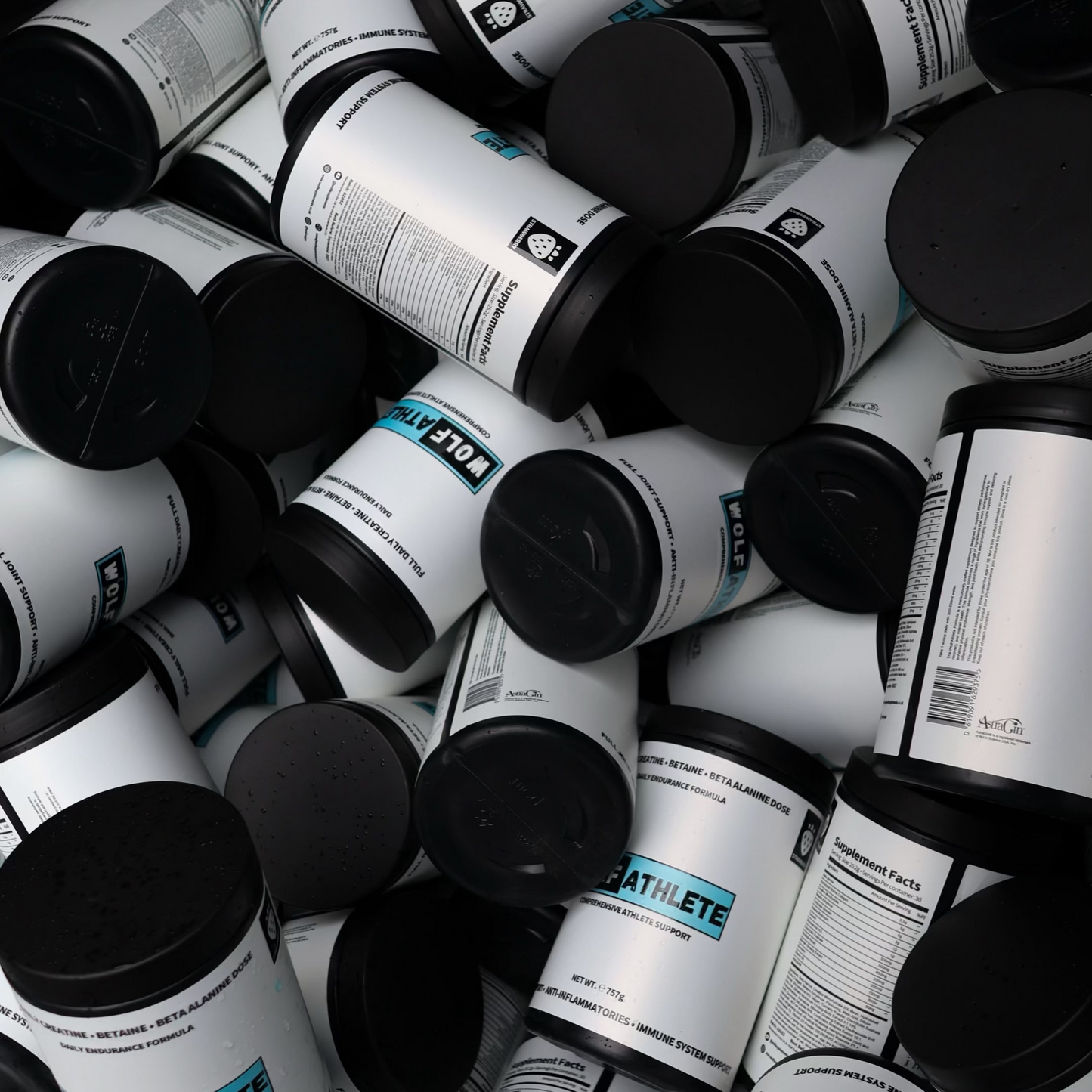 Pile of cylindrical containers with black lids and visible labels.