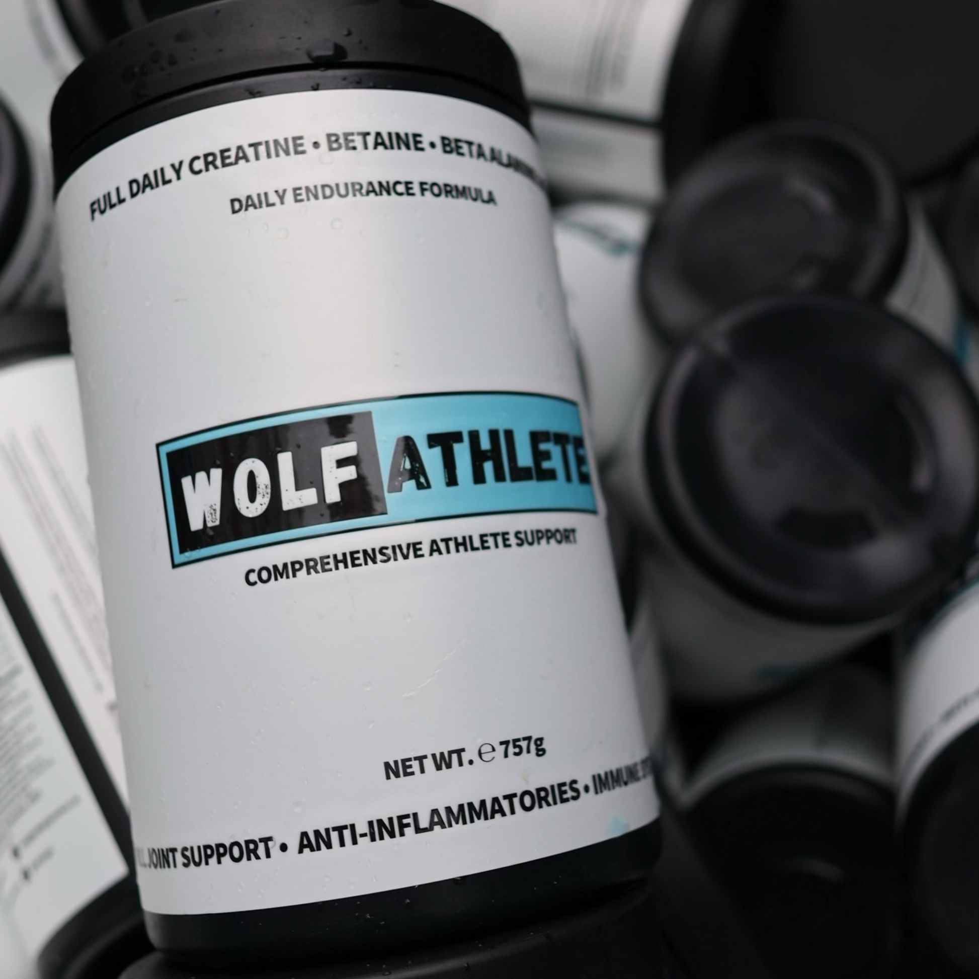A close-up of a stack of Wolf Athlete supplement tubs, with the top canister showing the brand logo and product details, surrounded by other tubs in a pile.